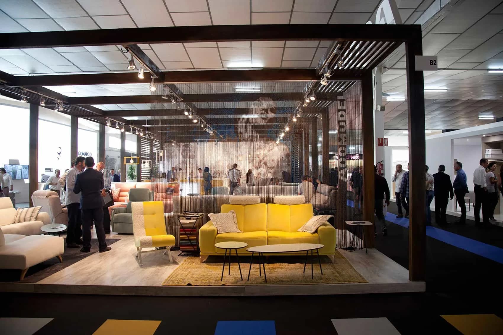 Stand de la Feria del Mueble de Yecla con sofás amarillos y visitantes