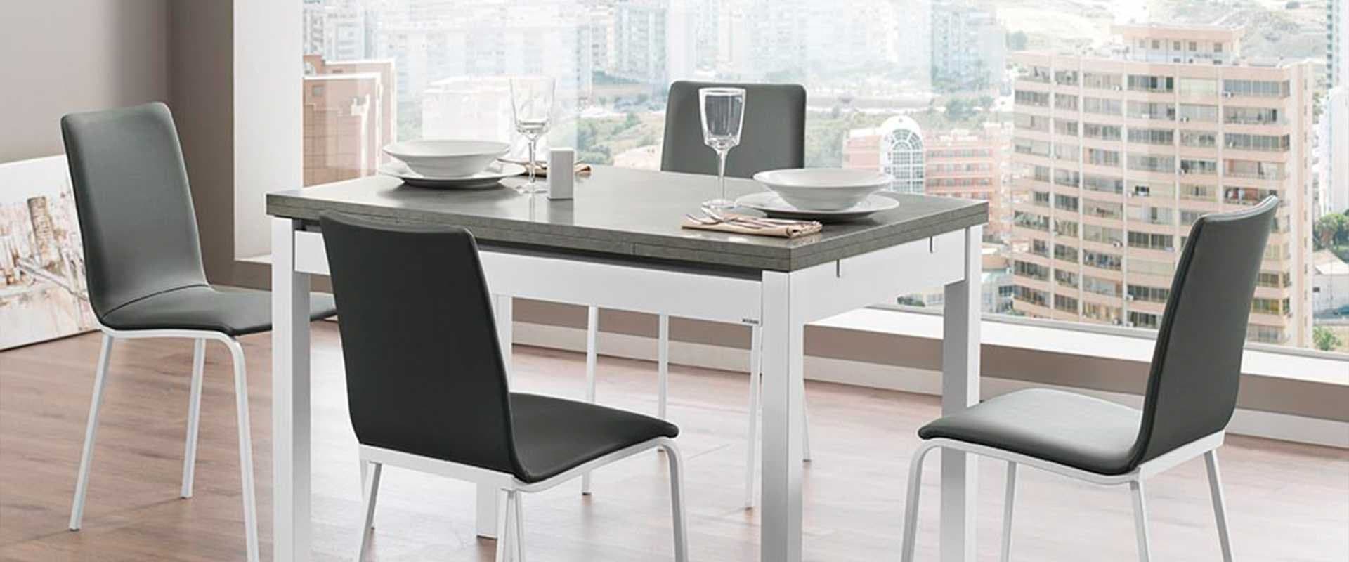 Mesa de comedor extensible con sillas tapizadas grises frente a una ventana con vistas a la ciudad