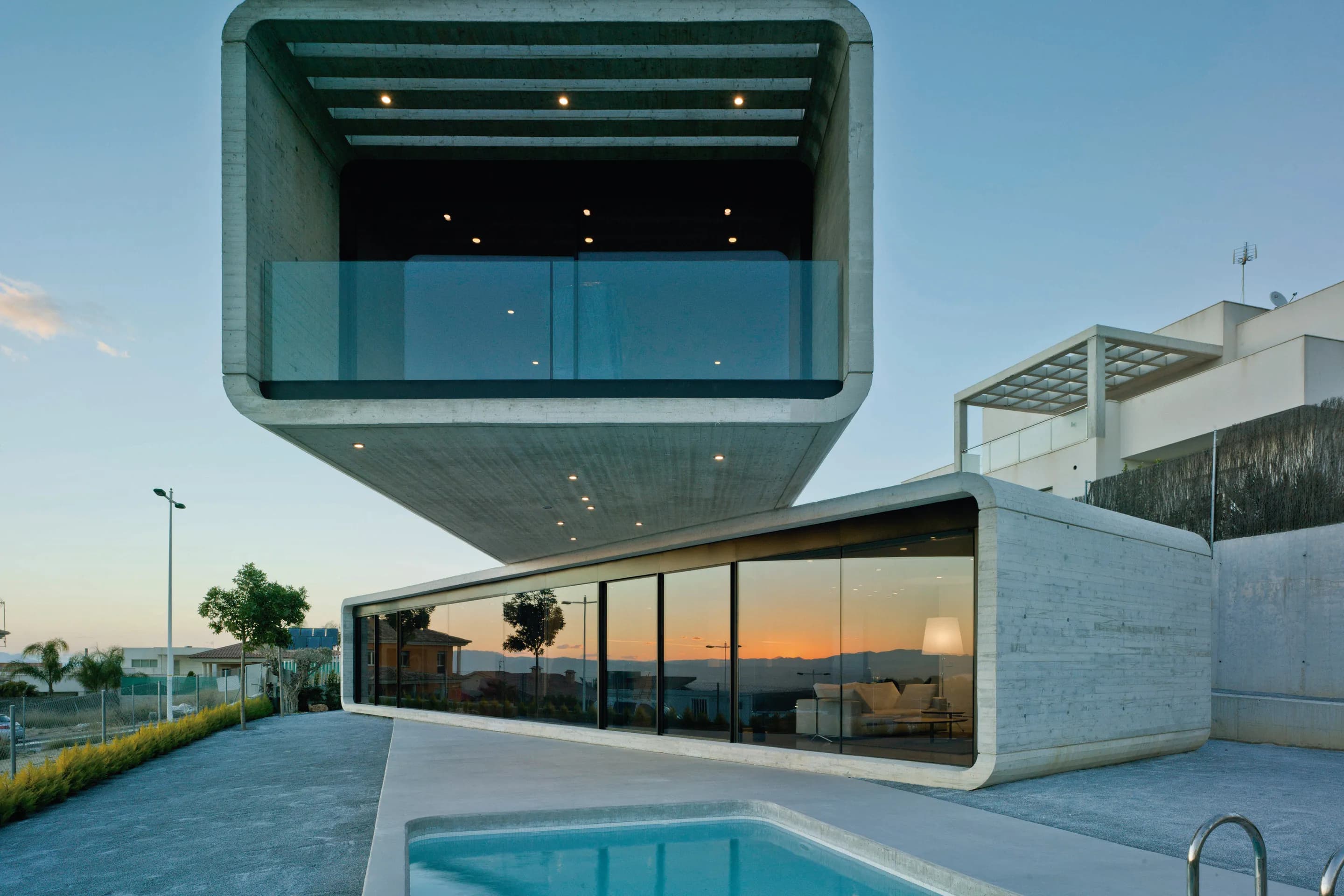 Vivienda unifamiliar moderna de hormigón en voladizo con piscina al atardecer