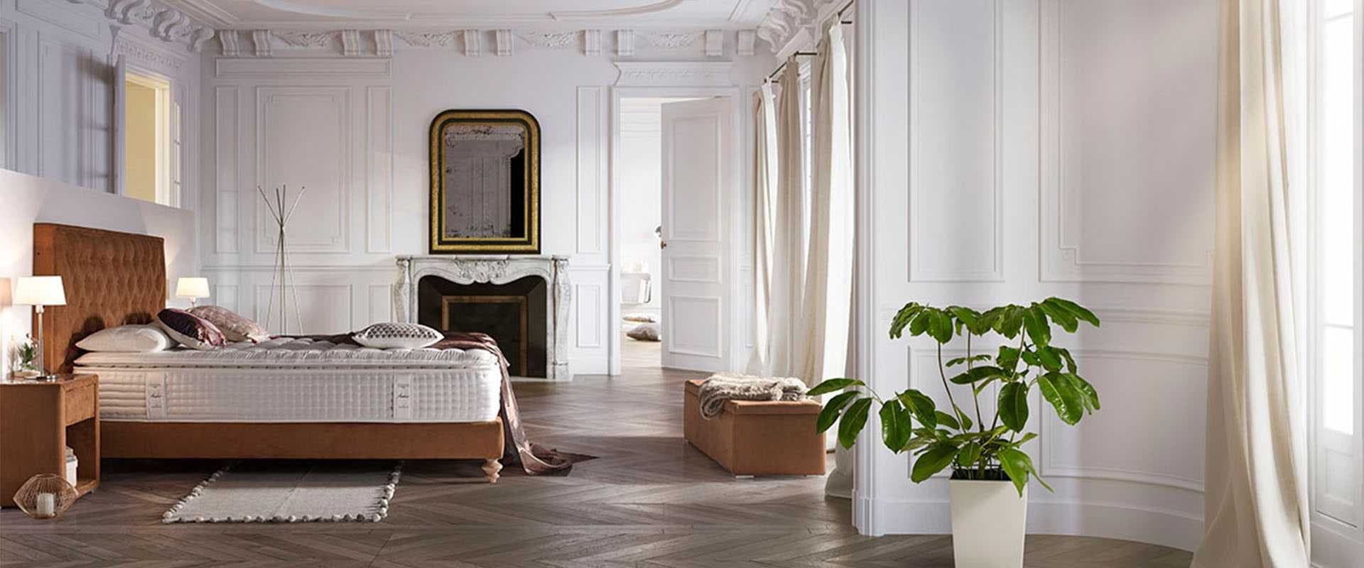 Dormitorio con cama de cabecero de madera, colchón de la marca y papel pintado con ramas