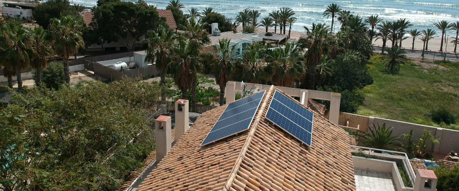 Vista aérea de una vivienda con placa solar térmica instalada en el tejado junto al mar