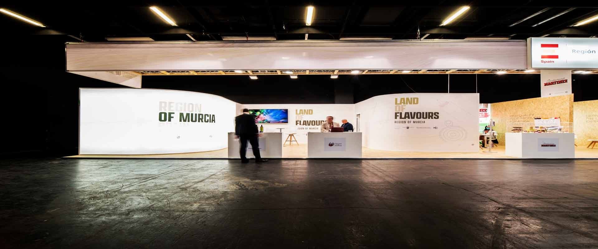 Stand "Region of Murcia - Land of Flavours" en una feria comercial, con mostradores y paneles blancos