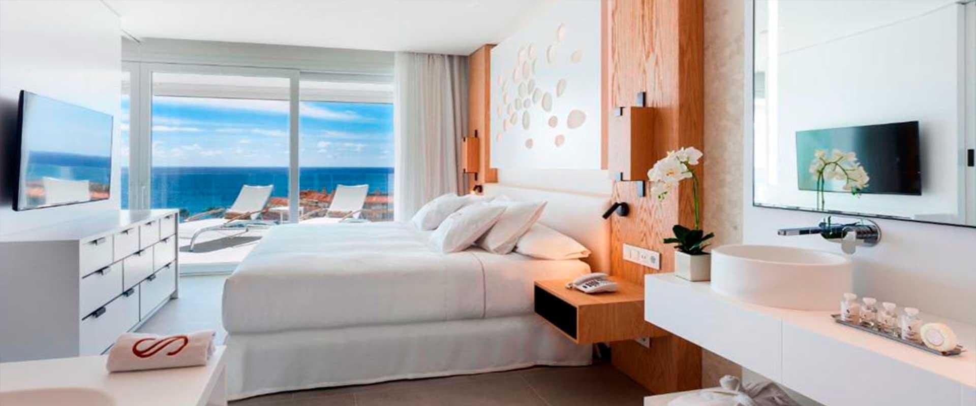 Habitación de hotel con cama doble, vistas al mar y toallas con el logotipo de la marca