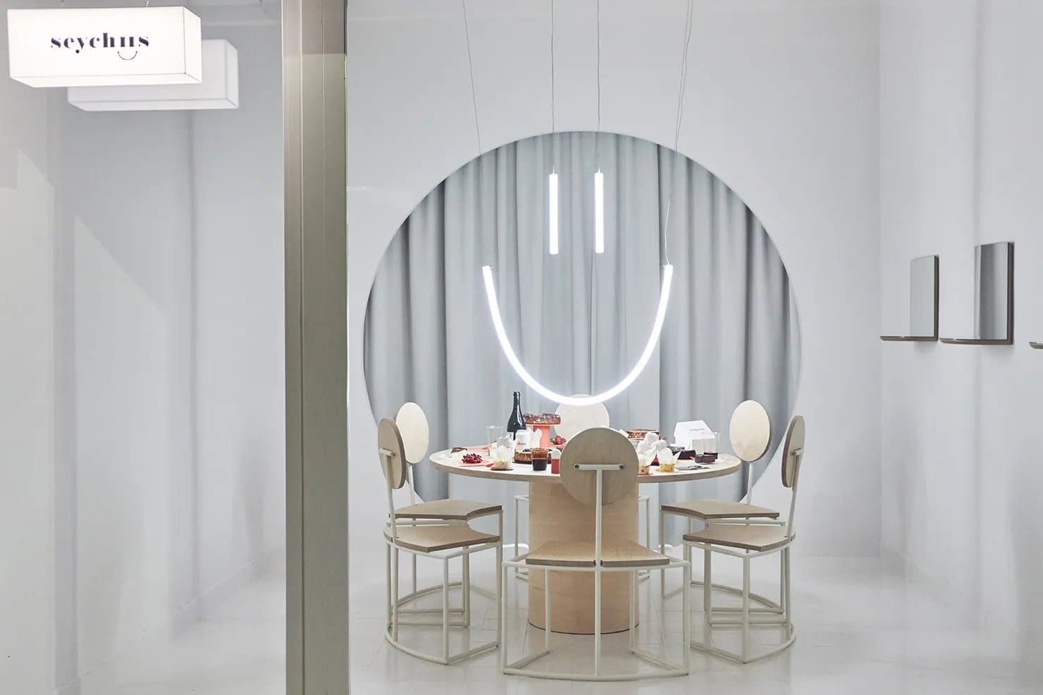 Tienda con mostrador circular, mesa redonda de madera y sillas de diseño bajo iluminación en forma de sonrisa