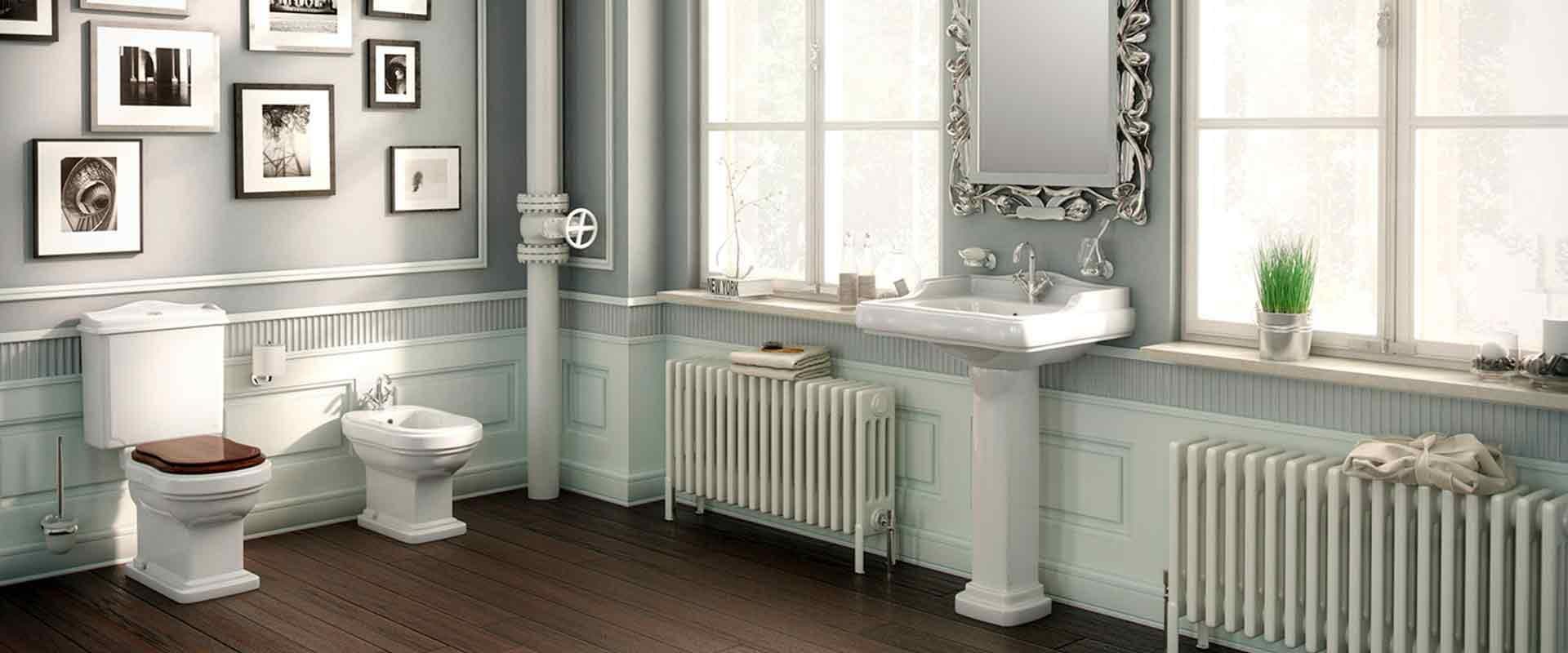 Cuarto de baño clásico con sanitarios blancos, fotografías enmarcadas en blanco y negro y radiadores