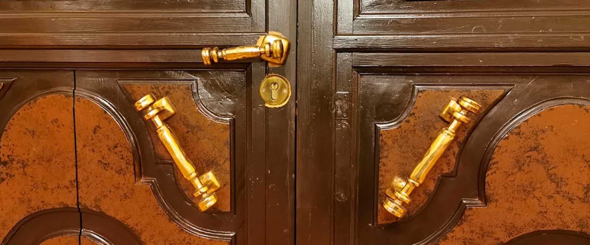 Tiradores y bisagras de latón dorado sobre las puertas de un mueble antiguo de madera oscura