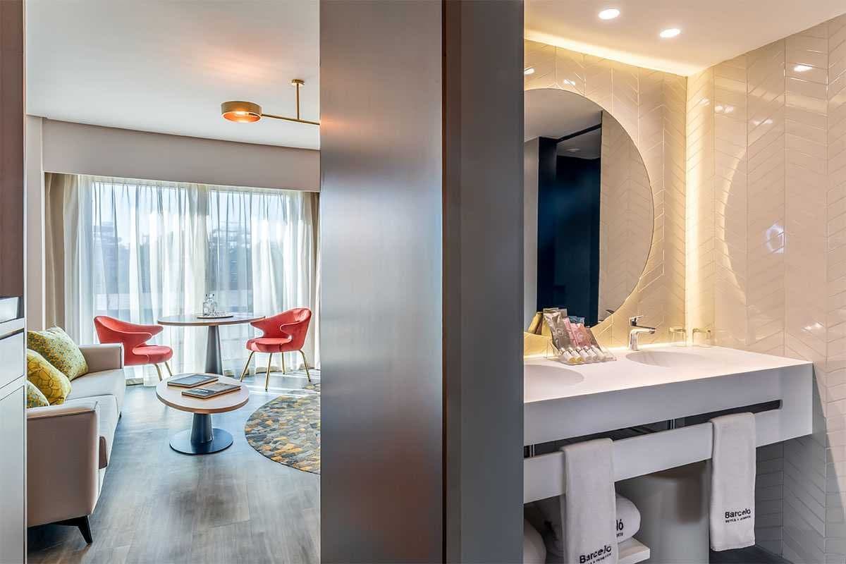 Imagen dividida de una suite de hotel con zona de estar y baño con toallas de la marca Barceló