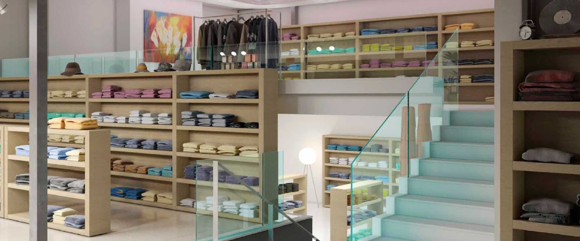 Tienda de ropa con estanterías de madera, prendas dobladas por colores y escalera acristalada