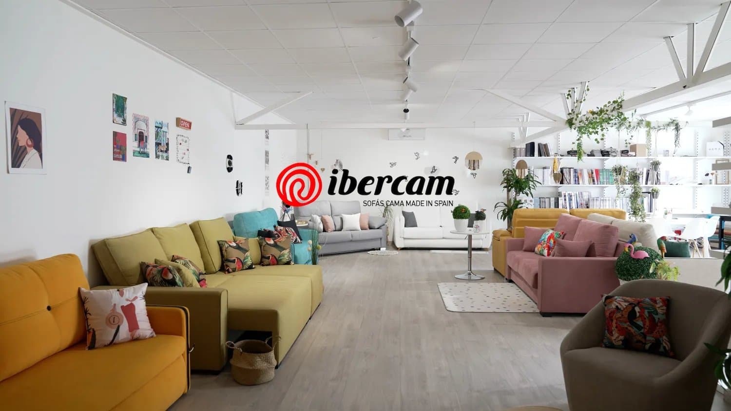 Showroom de sofás de colores con el logotipo de la marca Ibercam en la pared