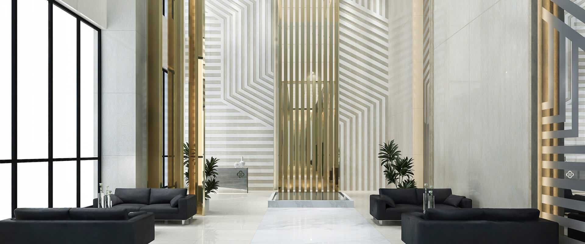 Lobby de hotel de techos altos con paneles dorados y grises y sofás negros