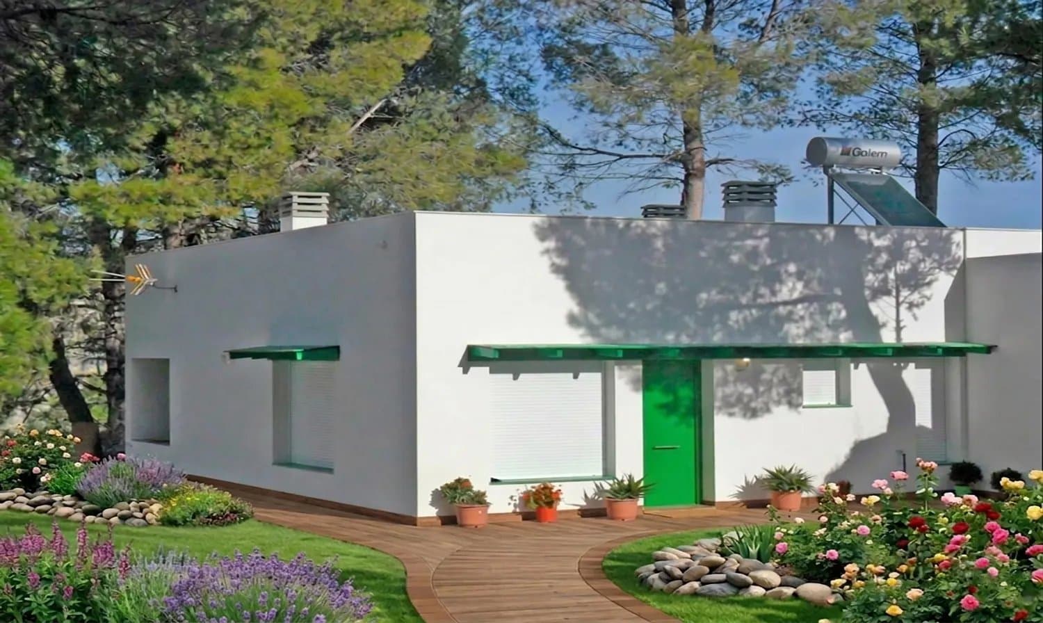Vivienda blanca de una planta con placa solar térmica en el tejado y jardín con flores