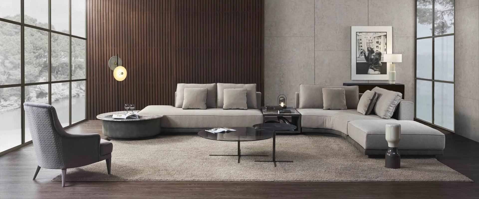 Salón con sofá seccional curvo en tonos grises y paneles de madera en la pared