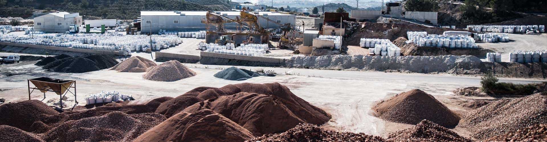 Vista aérea de una planta de áridos con montones de piedra triturada y sacos de materiales