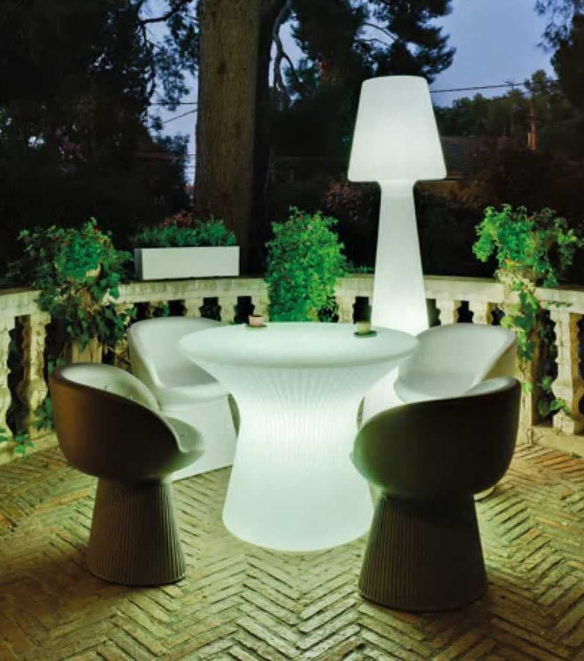 Terraza con mesa y lámpara exterior luminosas junto a sillones de resina