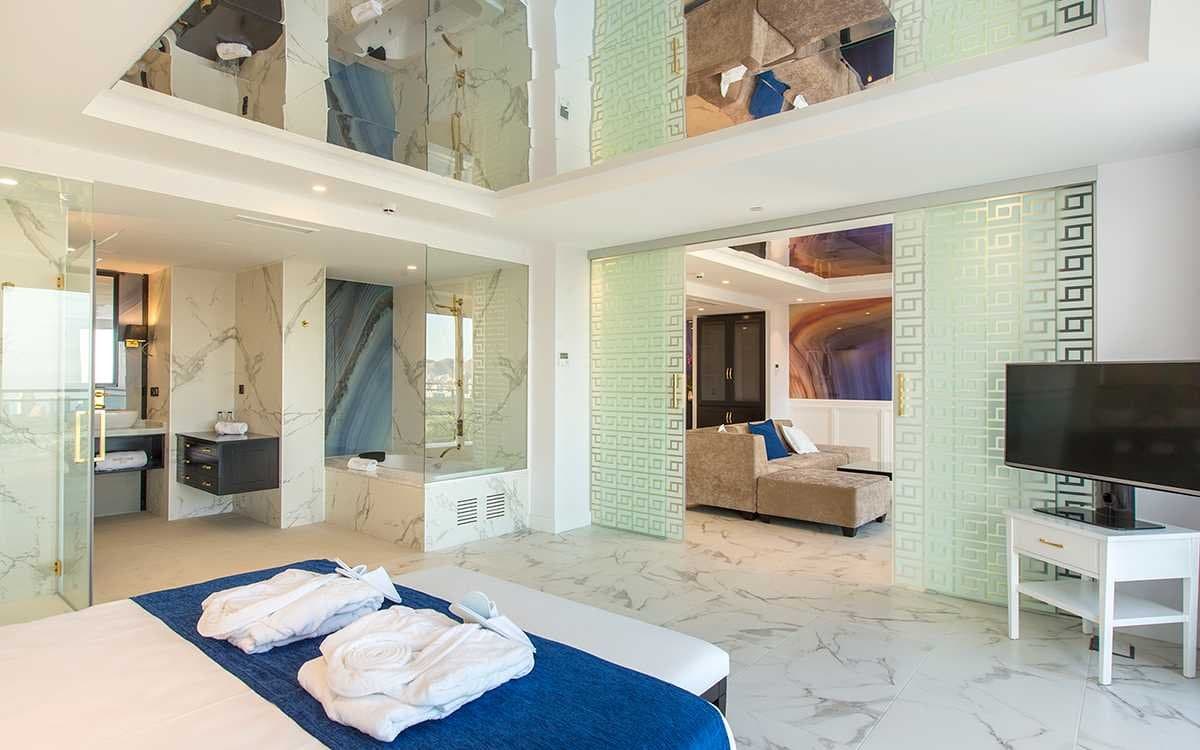 Suite con bañera junto a ventanal, mampara de cristal y puertas correderas con motivo geométrico verde