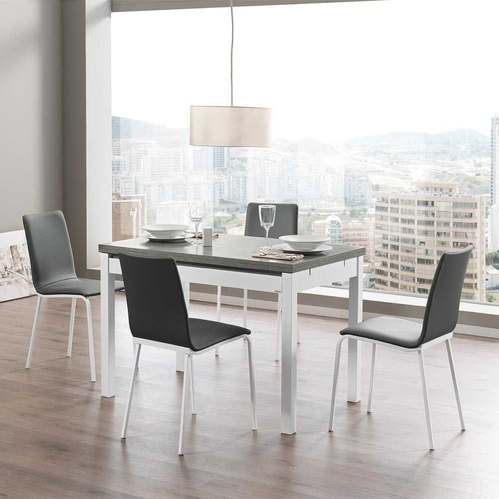 Mesa de comedor extensible gris y blanca con cuatro sillas tapizadas junto a un ventanal panorámico