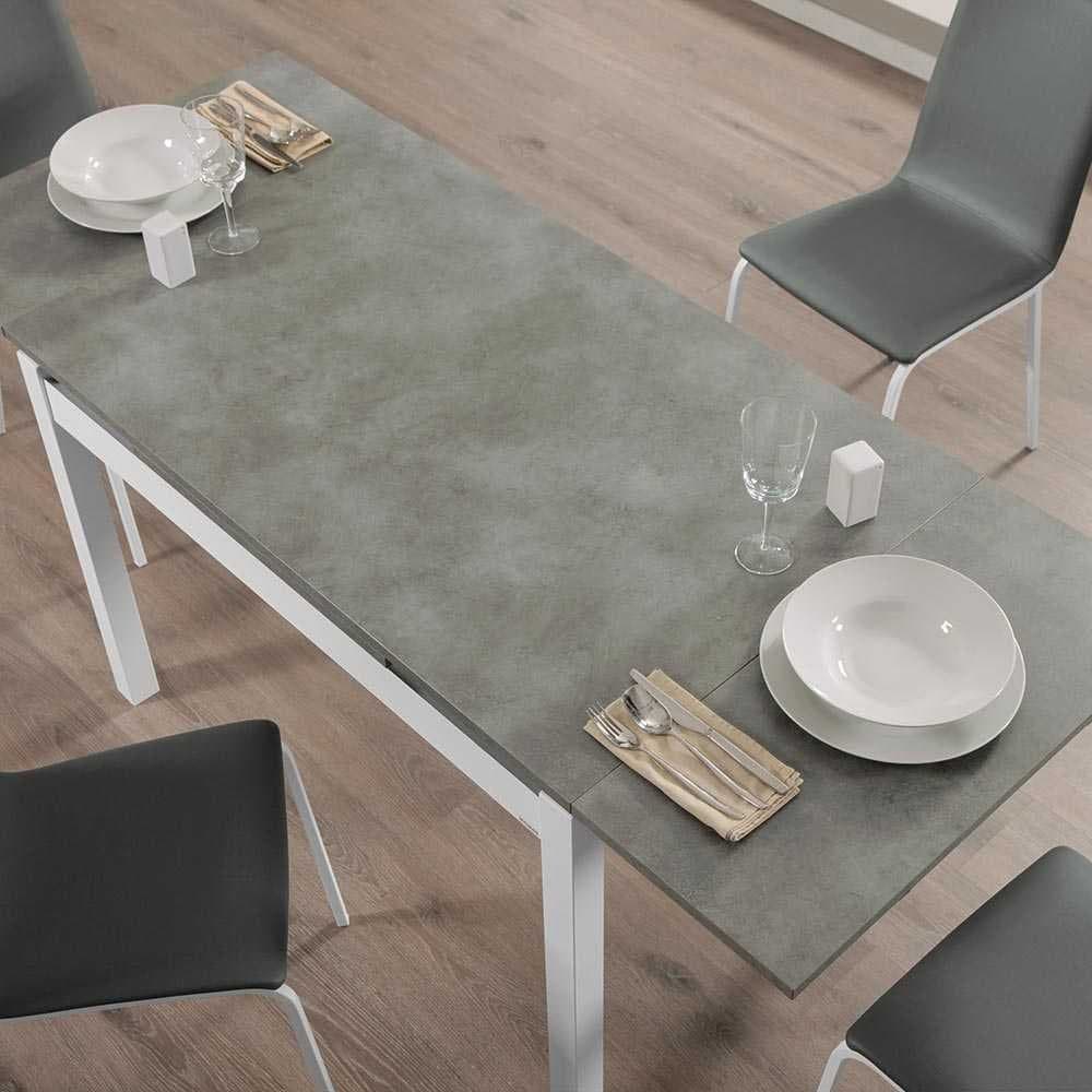 Vista cenital de la mesa puesta con platos, copa de vino y servilletas junto a sillas tapizadas grises