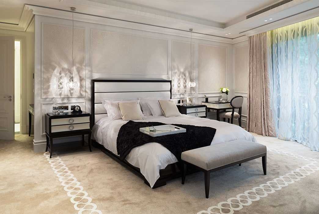 Dormitorio con cabecero tapizado negro y blanco, alfombra con motivo de cadenas y cortinas en rosa y azul