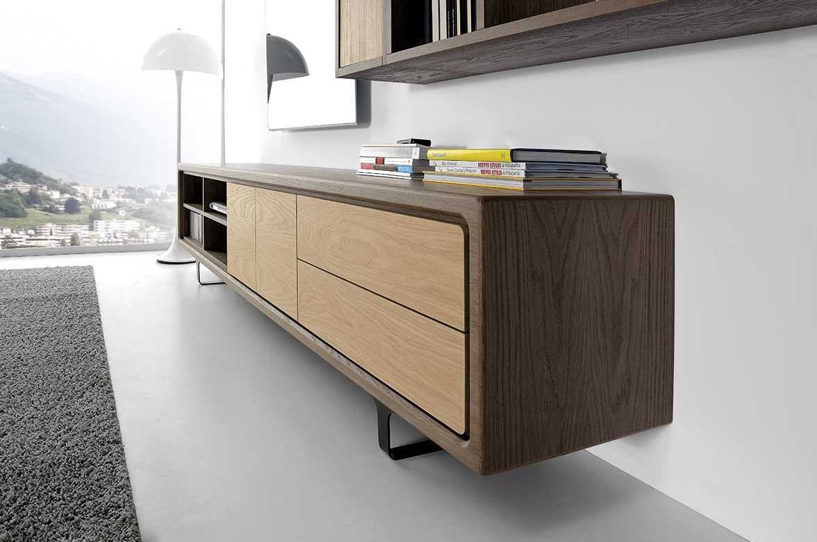 Detalle en perspectiva del mueble de salón suspendido con cajones en madera clara y revistas sobre la superficie