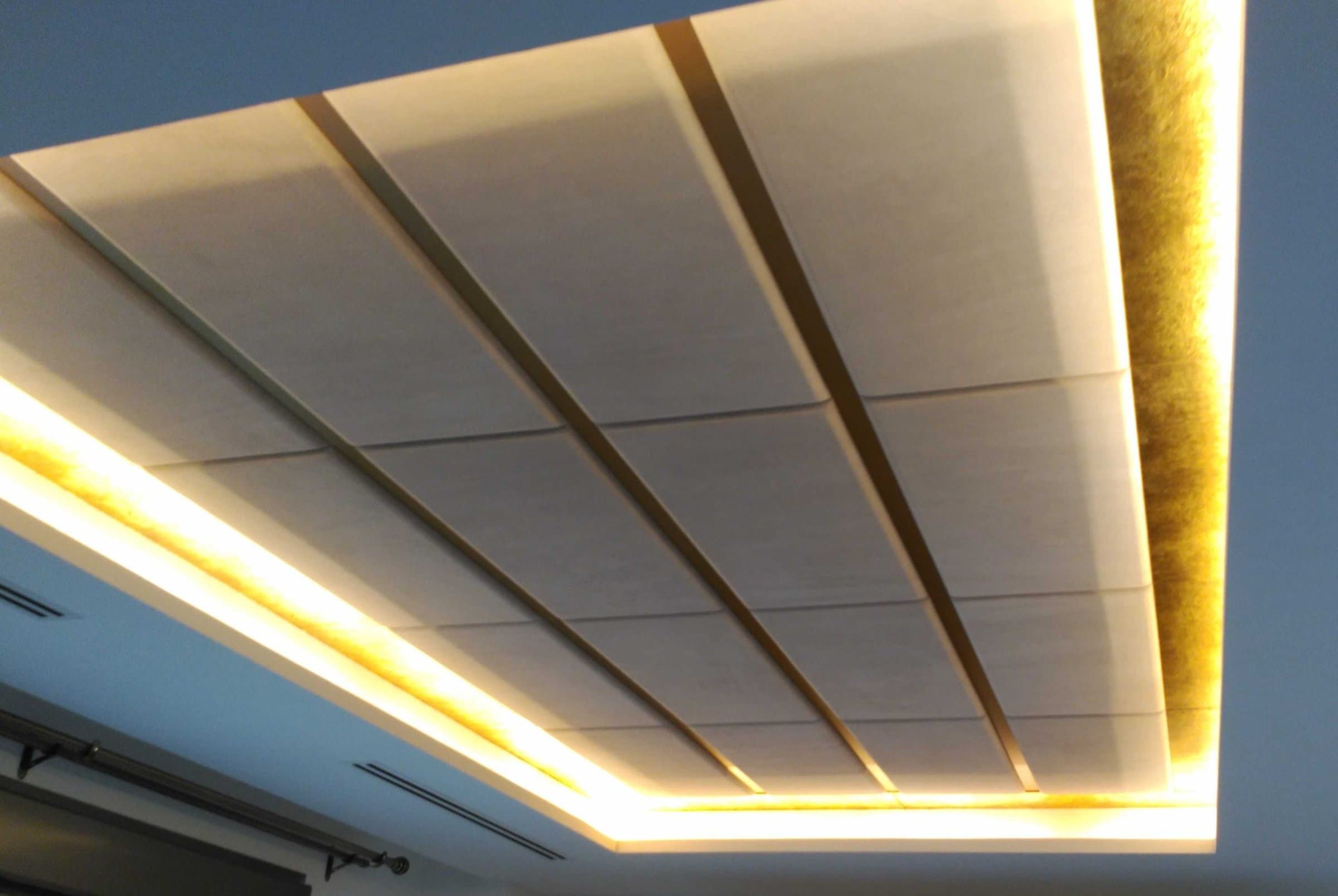 Detalle de techo con paneles acanalados en beige e iluminación LED perimetral dorada