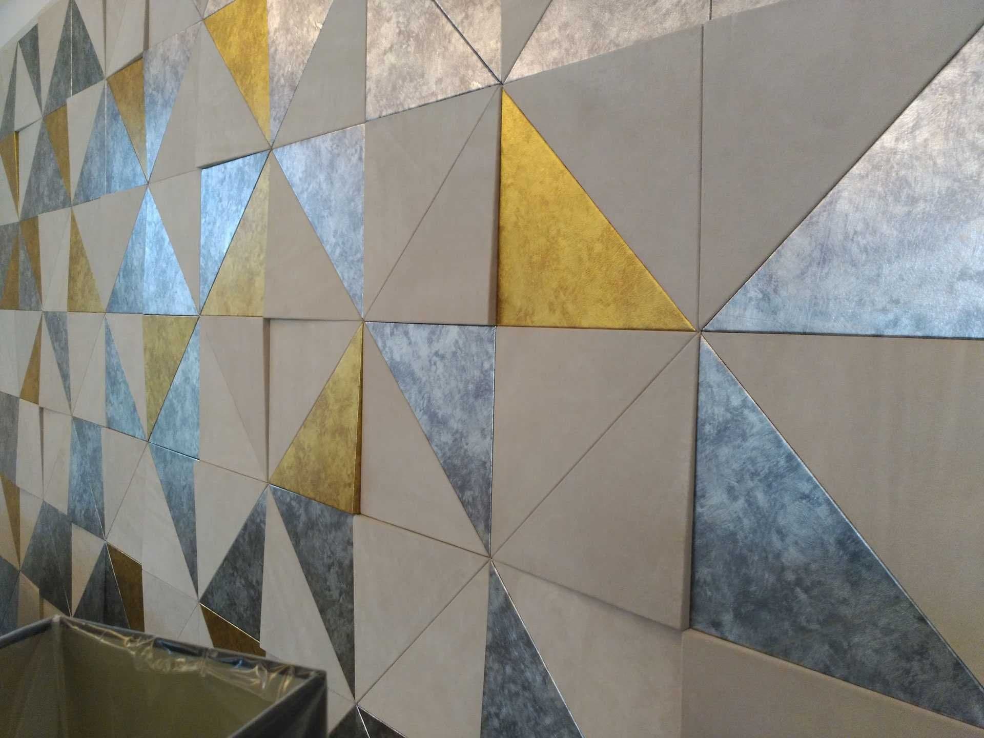 Detalle de mosaico de paneles triangulares en tonos dorado, plata y beige